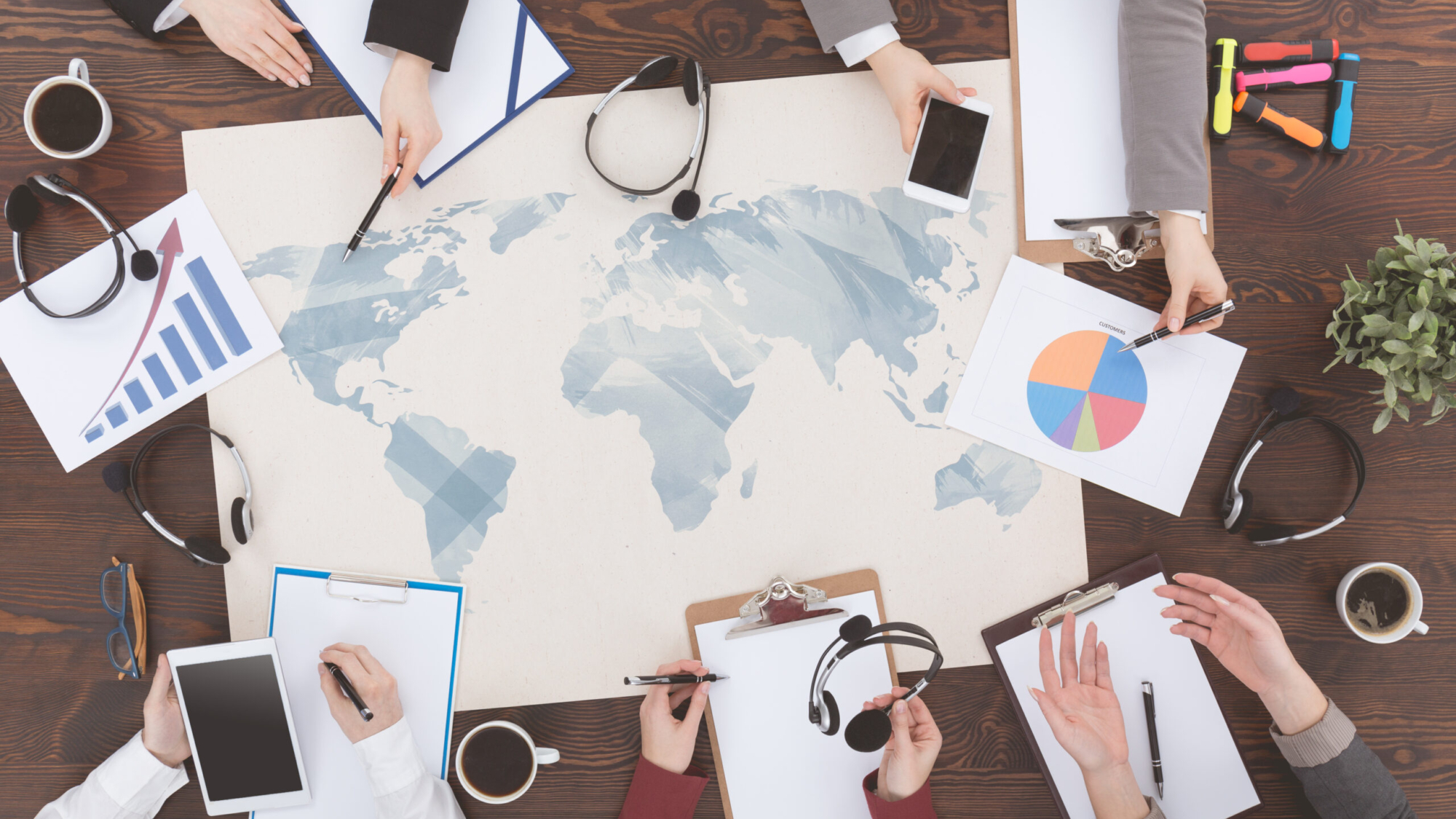 Telemarketers having a meeting around a wooden table with map of the world